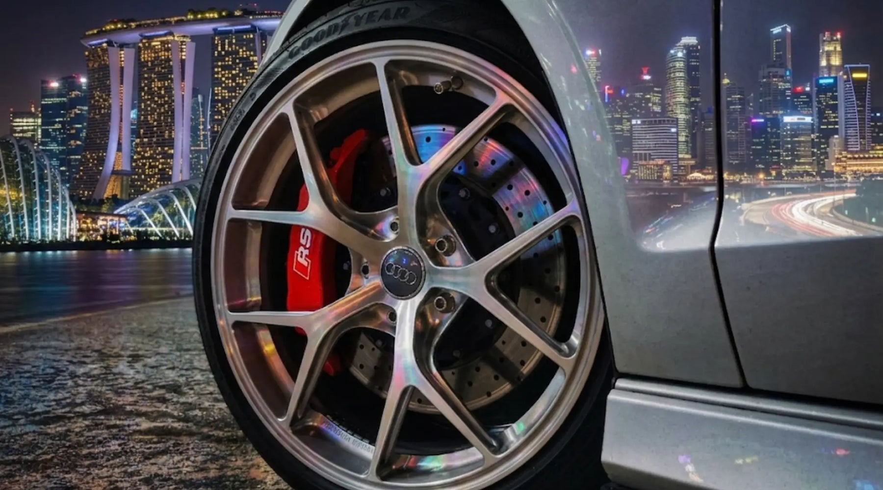 Custom 6061-T6 forged car rim and massive brake caliper on a dark sports car parked in Singapore at night.