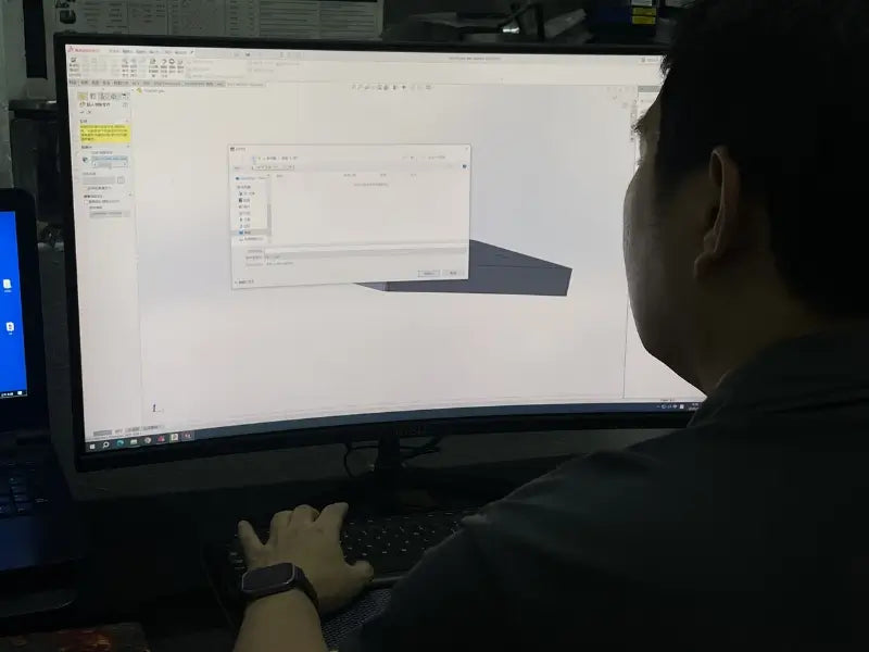 Person at RRT Forged using a computer with a large monitor displaying software interface creating forged wheels custom design